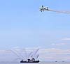 Plane with wing walker flies over fireboat